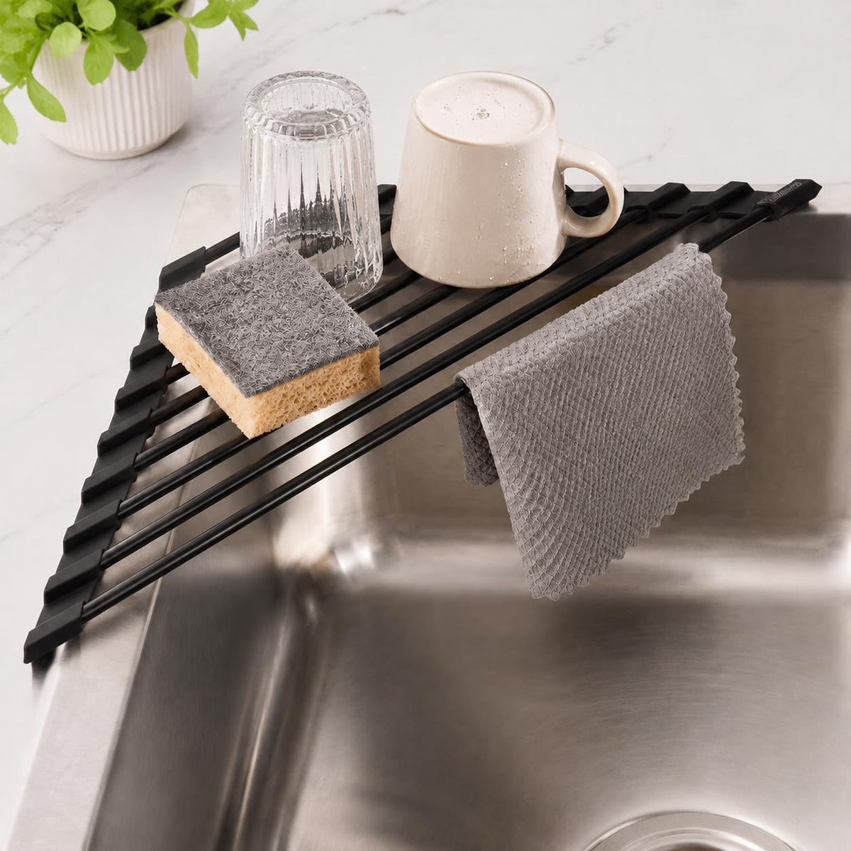 The black triangle rack across a sink corner holding a glass, mug, sponge and cloth