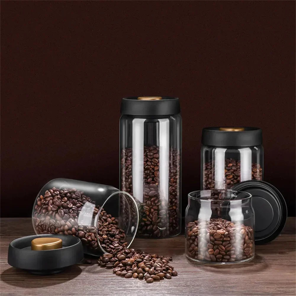 Three vacuum coffee canisters of different heights against a dark background, beans visible through the glass.